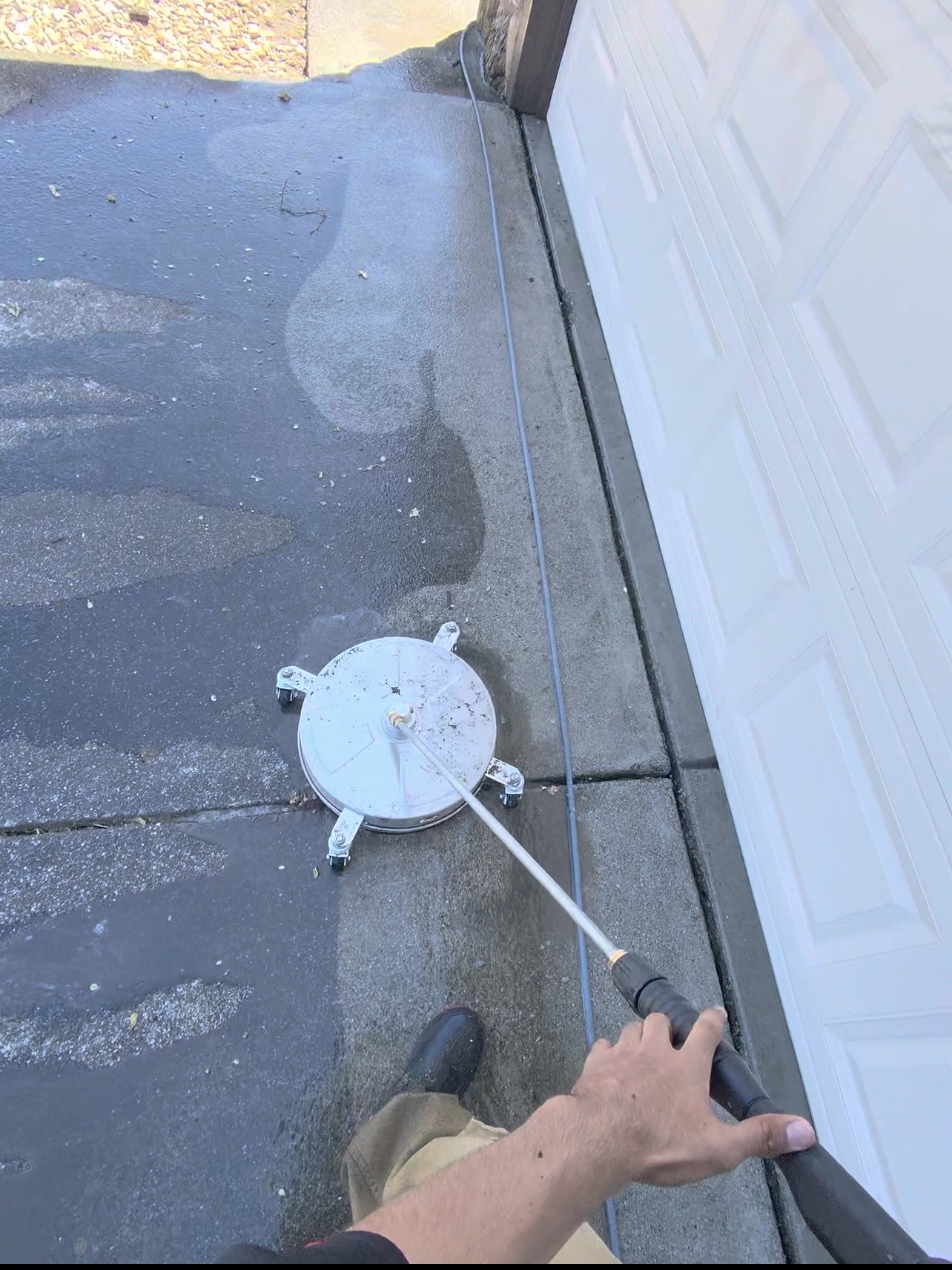 CAMTERRA technician pressure washing a driveway with a surface cleaner
