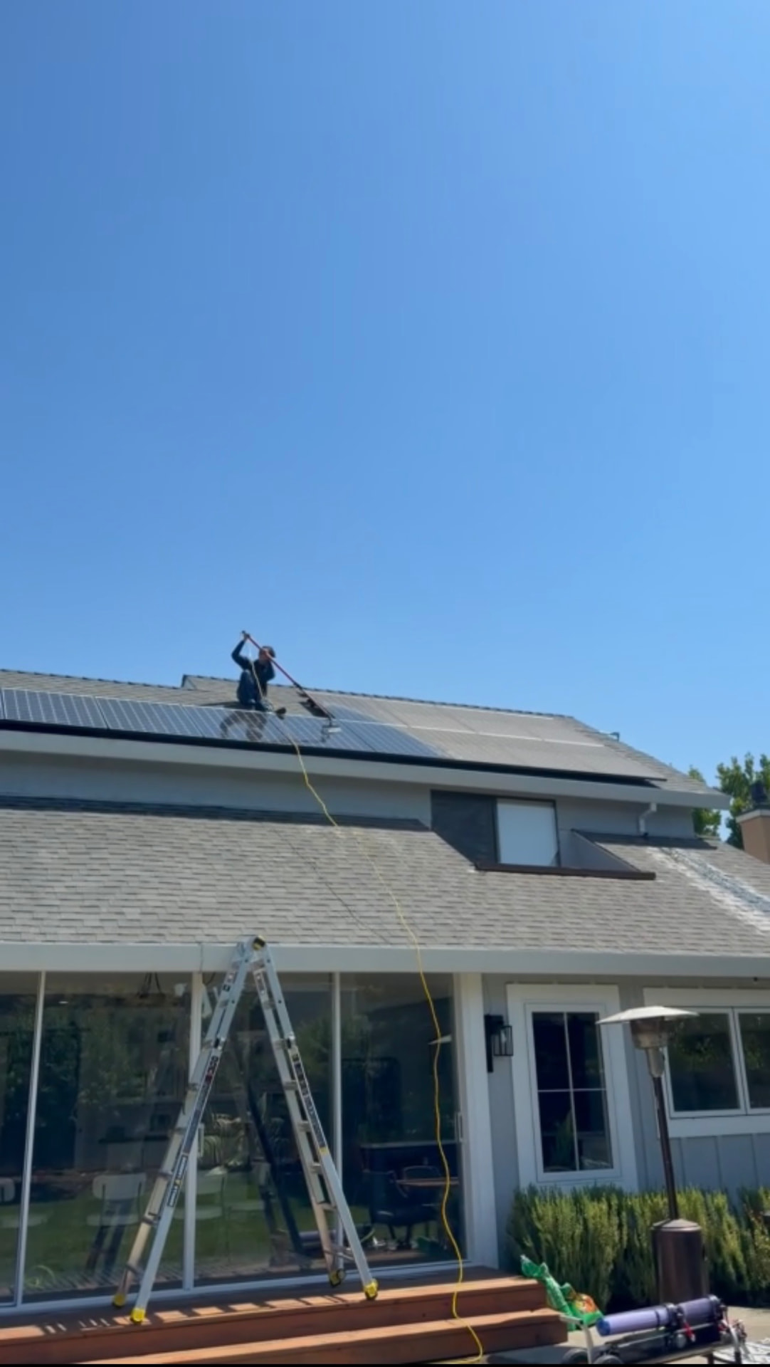 CAMTERRA technician cleaning rooftop solar panels on a sunny day
