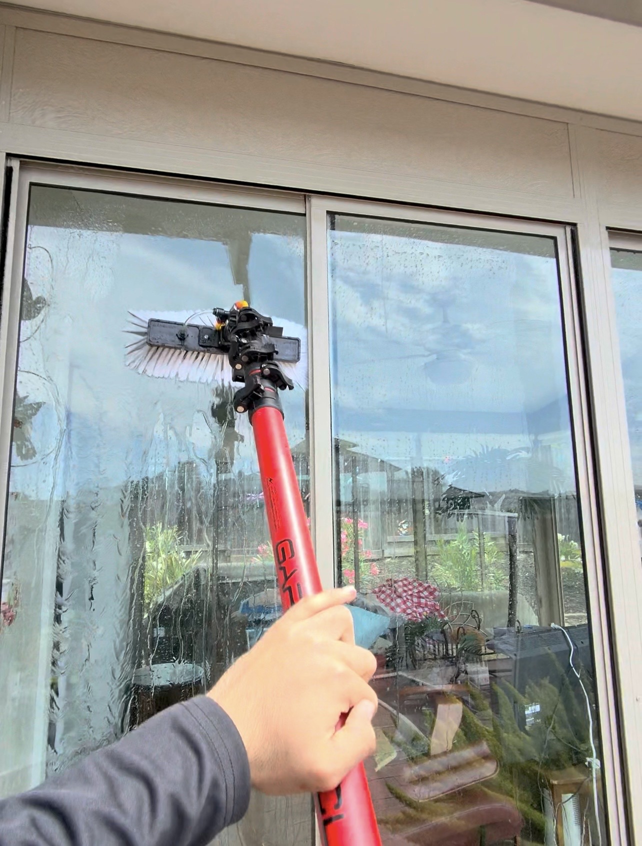 CAMTERRA technician cleaning a sliding glass door with a water-fed pole brush